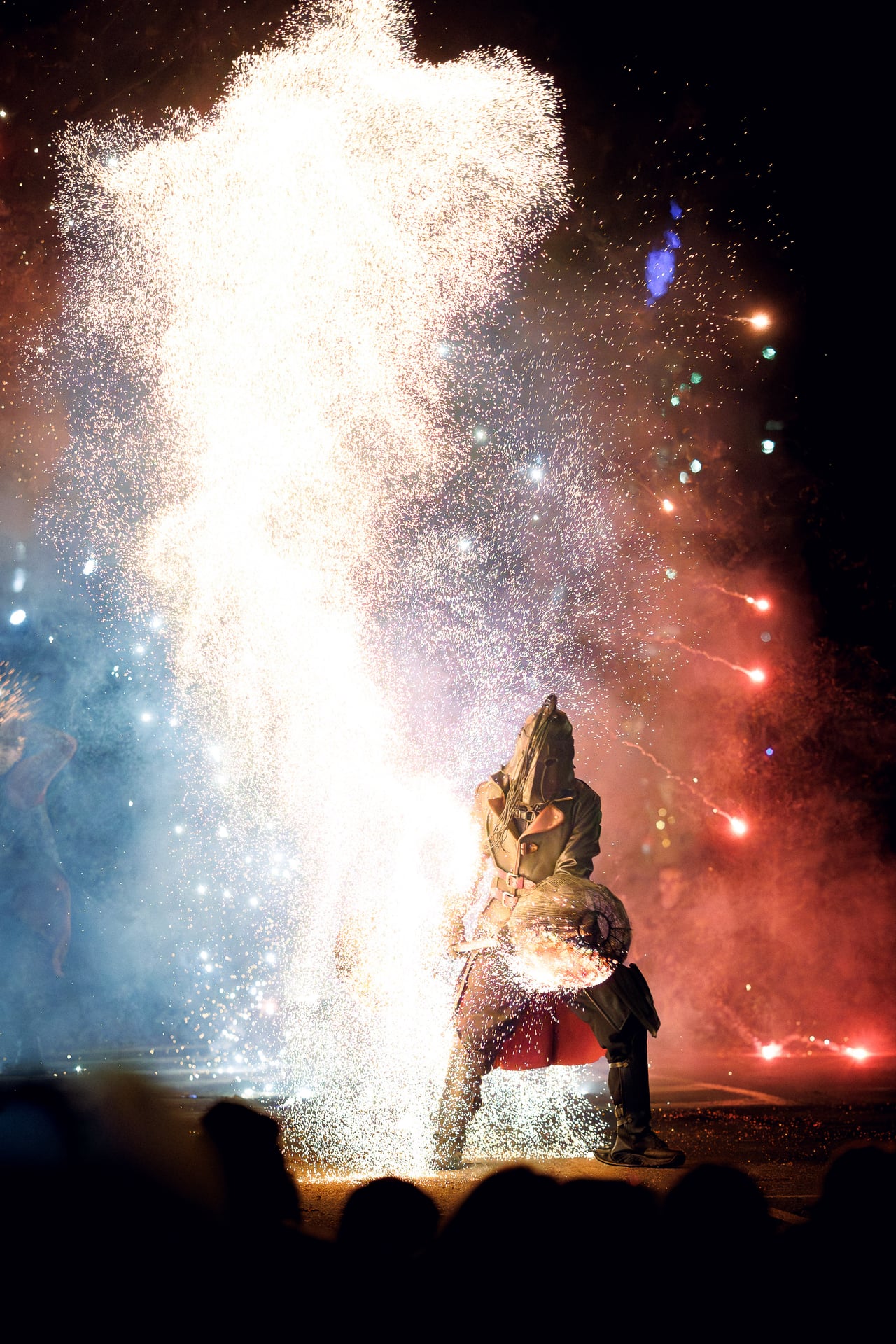 Artiste sous une gerbe d’étincelles pendant le spectacle de feu