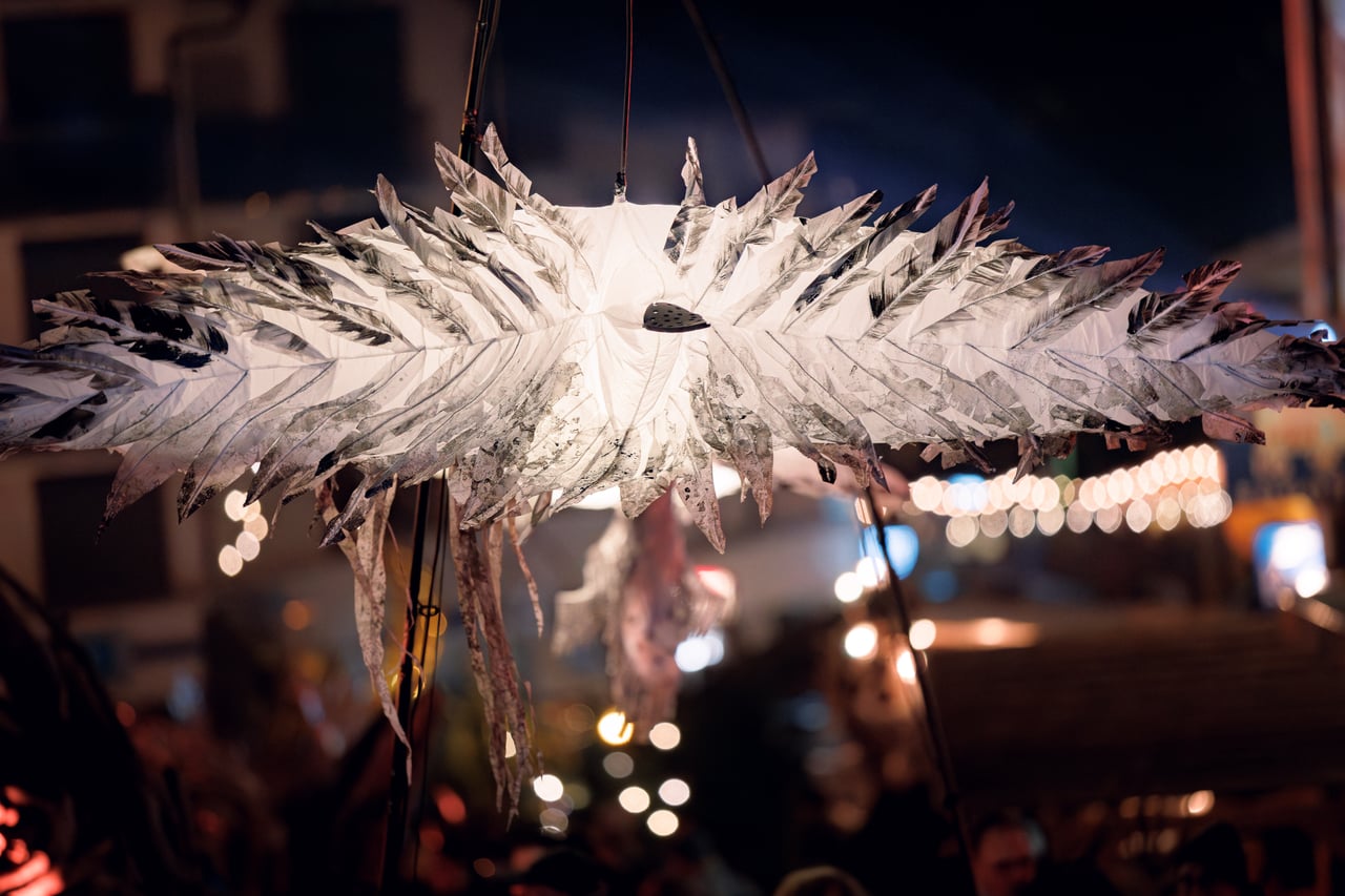 A giant lit-up bird above the crowd, Fabuleux Village des Flottins in Évian