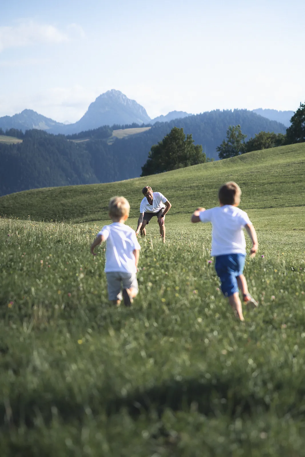 Enfants d'une famille qui court dans un pré lors d'une séance photo de famille.